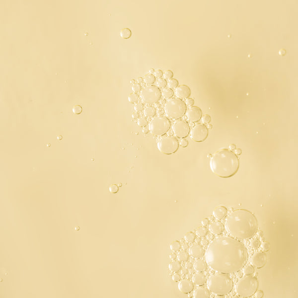 Close-up texture image of golden liquid bubbles suspended against a soft cream background.