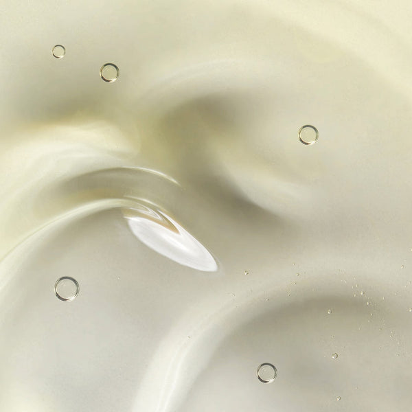 Close-up of a smooth, translucent golden gel texture with small air bubbles, showcasing the lightweight, cleansing consistency of Tropic’s Clarifying Hair Wash.