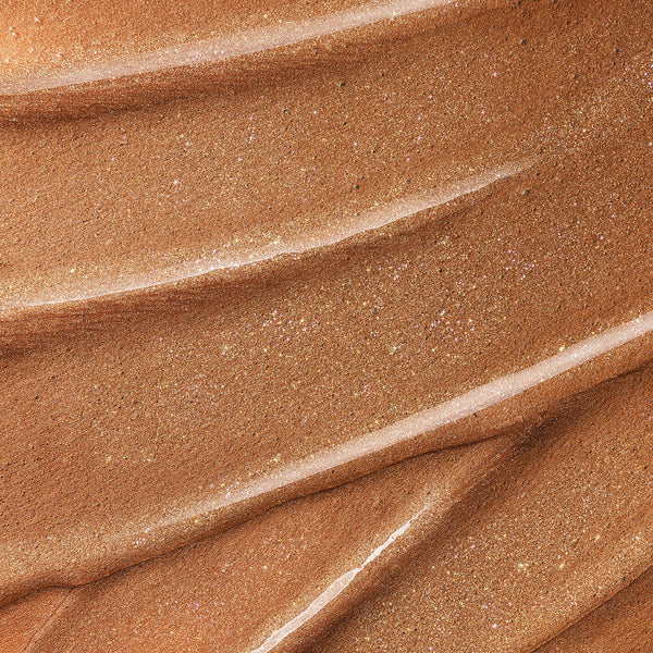 Close-up texture of bronze shimmering serum with smooth, glossy ridges and fine golden sparkle.
