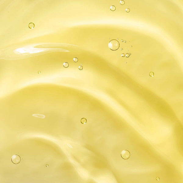 Close-up of smooth golden-yellow baby oil texture with gentle ripples and small air bubbles, highlighting its light, nourishing consistency.