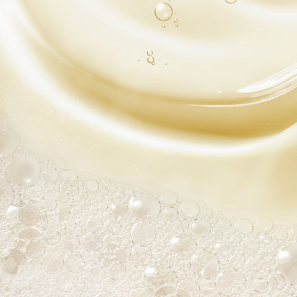 Close-up texture of Tropic Luxury Bath Foam, showing silky golden liquid with delicate, airy bubbles that create a rich, luxurious lather.