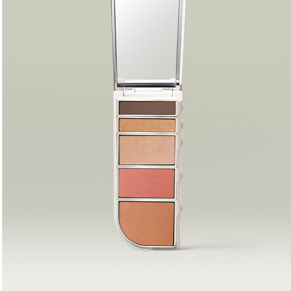 A sleek, open makeup palette with five pans in warm neutral shades-deep matte brown, shimmery gold, champagne highlight, coral blush, and bronze—shown vertically with a built-in mirror at the top.