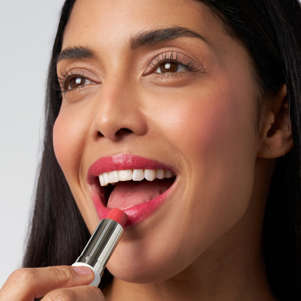 Close-up of a woman applying Tropic Butter Tint, showing a pink shade on her lips.