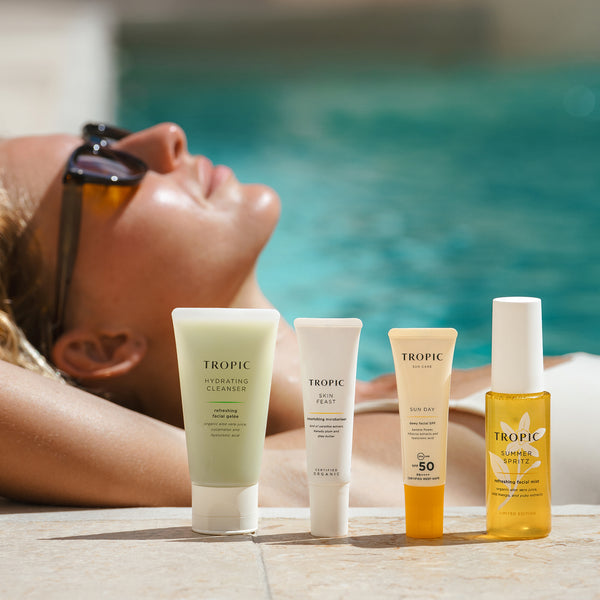 Travel-sized Carry-On Collection beside a swimming pool, including cleanser, moisturiser, SPF 50+ and Summer Spritz facial mist.