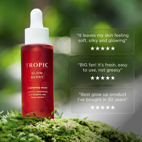 Tropic Glow Berry brightening serum bottle on moss with customer review quotes and five-star ratings displayed beside it.