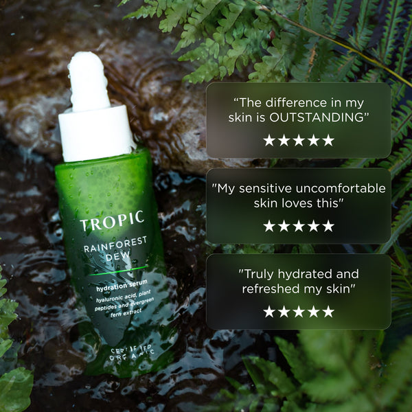 Tropic Rainforest Dew hydration serum bottle in flowing water surrounded by ferns, with customer review quotes and five-star ratings displayed beside it.