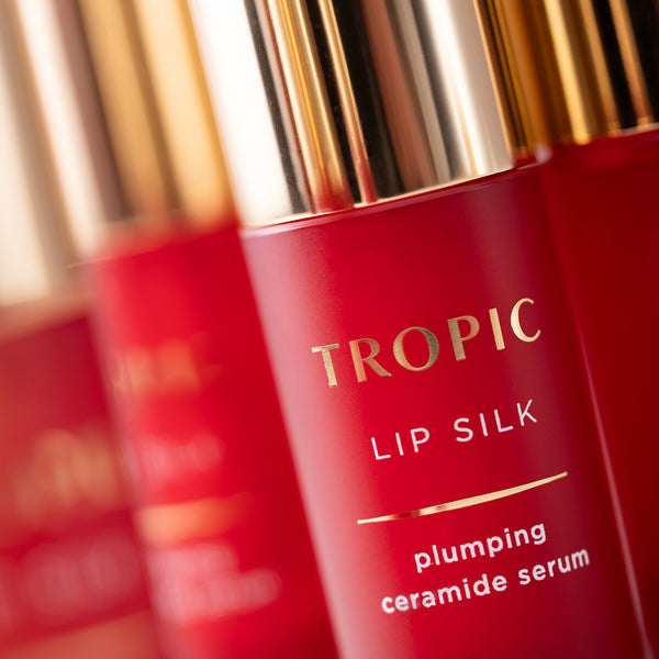 A close-up of Tropic Lip Silk bottles highlighting the red packaging and gold detailing.