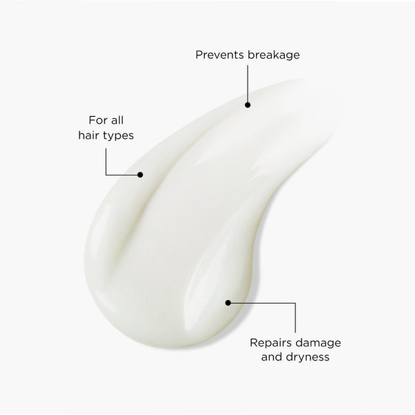 Close-up of a creamy white hair cleanser swatch labelled with benefits: “For all hair types,” “Prevents breakage,” and “Repairs damage and dryness,” illustrating the smooth, nourishing texture of Tropic’s Nourishing Hair Cleanser.