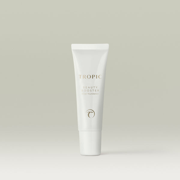 A white tube of Tropic Beauty Booster sheer foundation standing upright against a soft neutral background.