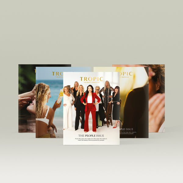Five Tropic Beauty Brochures fanned out, with a central cover showing a group of women led by one in a red suit, surrounded by lifestyle skincare imagery.