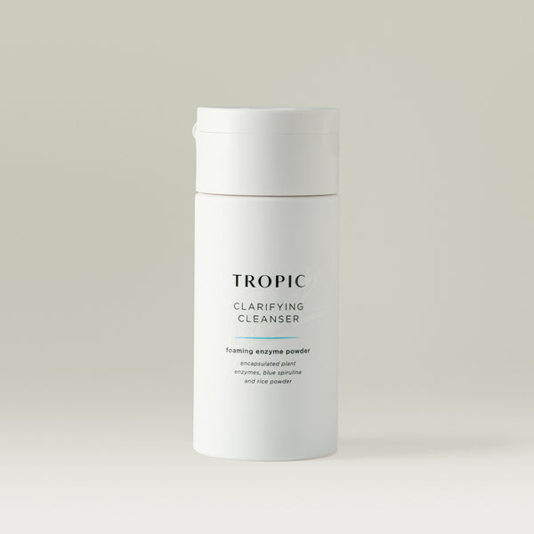 Tropic Clarifying Cleanser Foaming Enzyme Powder in a sleek white bottle, formulated with encapsulated plant enzymes, blue spirulina, and rice powder to gently exfoliate and purify the skin.
