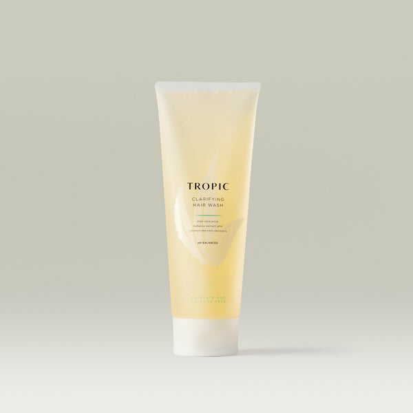 Tropic Clarifying Hair Wash in a translucent golden tube with white cap, featuring minimalist branding. The gentle formula with aloe vera juice, babassu extract, and coconut-derived cleansers is designed for a sulphate- and silicone-free deep clean.