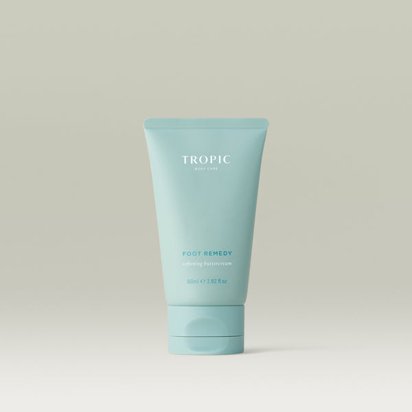 Tropic Foot Remedy softening buttercream in a blue tube on a neutral background.