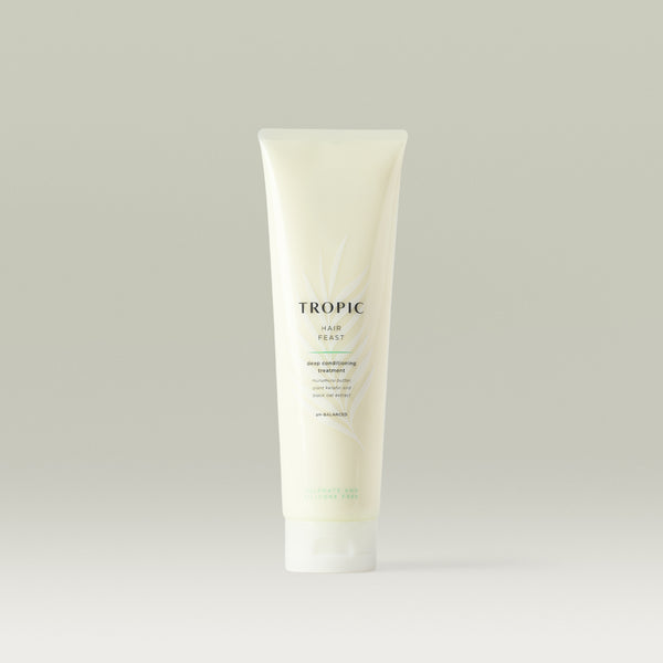 Tropic Hair Feast Deep Conditioning Treatment tube standing upright against a soft neutral background, showcasing its nourishing formula designed to deeply hydrate and strengthen hair.