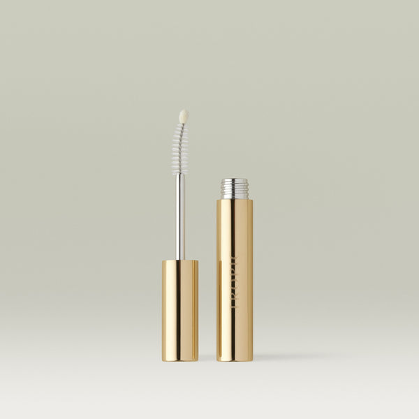 Open Lashful Eyelash Growth Serum featuring its gold tube and innovative dual-ended applicator with spoolie brush and precision tip, displayed on a reflective surface.