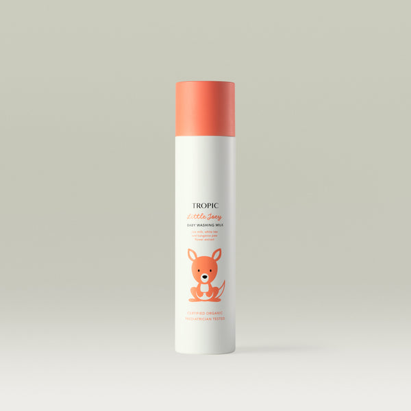 Tropic Little Joey Baby Washing Milk bottle with coral-orange cap and cute kangaroo illustration on a light background. Text mentions oat milk, white tea, and kangaroo paw flower extract.