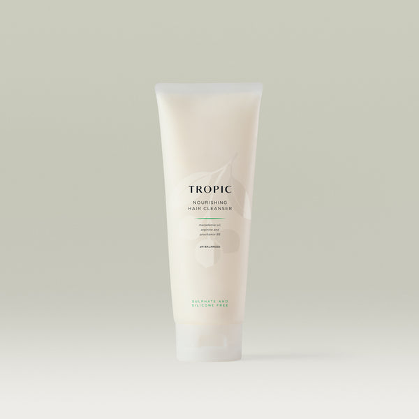Tropic Nourishing Hair Cleanser tube standing upright on a neutral background, featuring minimalist design and text highlighting key ingredients like macadamia oil, arginine, and provitamin B5.