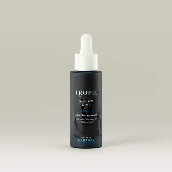 Tropic Ocean Dive Pore-Clearing Serum in a sleek dark blue bottle with a white dropper cap, formulated with blue algae, glucosamine, and salicylic acid to purify pores and promote clearer skin.