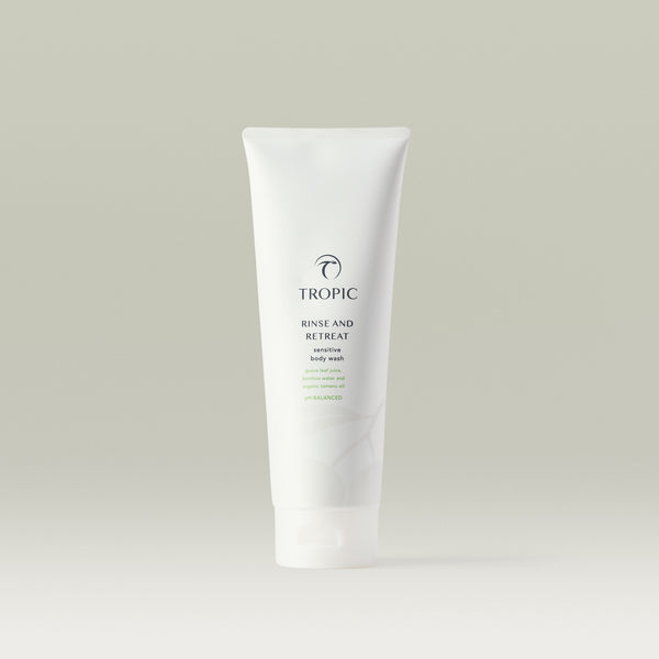 Tropic Rinse and Retreat Sensitive Body Wash in a sleek white tube with minimalist green accents, featuring guava leaf juice, bamboo water, and organic tamanu oil.