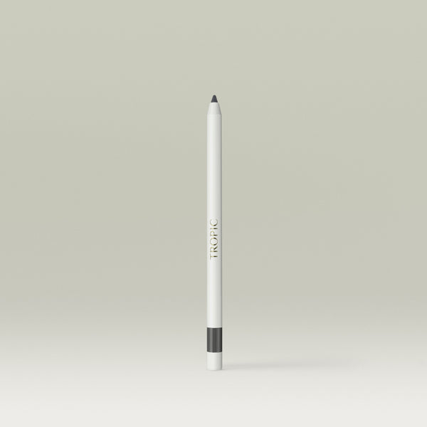 A white pencil-style eyeliner with a soft grey tip and a grey band near the base, shown standing upright against a soft, neutral background.