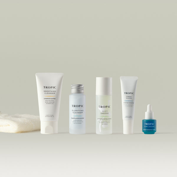 Tropic Skincare Discovery Kit Balance featuring Smoothing Cleanser, Clarifying Cleanser, Juicy Greens, Fresh Waves and Pure Lagoon arranged on a neutral background beside a folded white bamboo cloth.