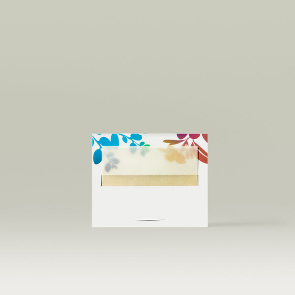A pack of Tropic Soft Veil Blotting Petals featuring a white case with colourful floral designs and a translucent window revealing the delicate blotting papers inside, set against a neutral background.