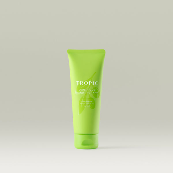 Bright green Tropic tube labelled “Superfood Hand Therapy,” enriched with olive squalane, papaya extract, and oat milk, displayed on a neutral background.