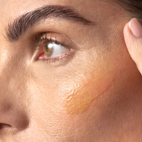 Close-up of skin with a smooth, glossy layer of product applied showing a rich, nourishing texture and radiant finish.