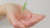 Model uses the pipette to drop a few drops of rainforest dew serum into the palm of their hand. They then press into their skin.