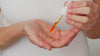 Model dispenses Elixir oil with the pipette into the palm of their hand. They rub their hands together and apply the product onto their face in sweeping motions and then down onto their neck.